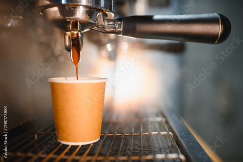 Foto Espresso coffee brewing into disposable paper cup