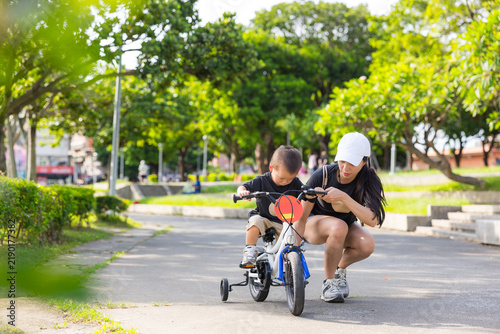 Fotografía Mother helping her young child ride a small bicycle on a path in Taiwan