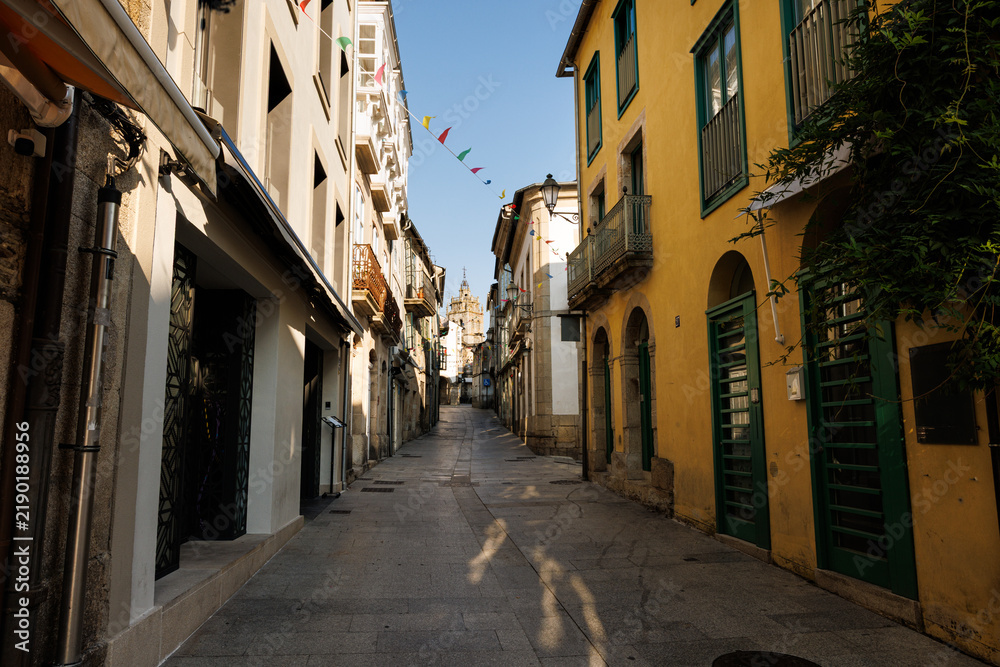 Fototapeta premium Narrow Cobblestone Street with Historic Buildings and Distant Be