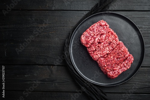 Konstfotografi Raw minced beef on matte black ceramic plate set atop dark rustic wooden surface