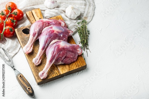 Obraz na plátně Three raw duck legs resting on a wooden cutting board beside fresh garlic cloves