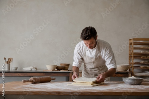 Baker folding dough on a flour dusted worktable