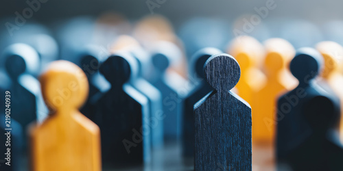 Dark wooden person figure standing out from a crowd of yellow pawns representing leadership, candidate recruitment, and HR selection.