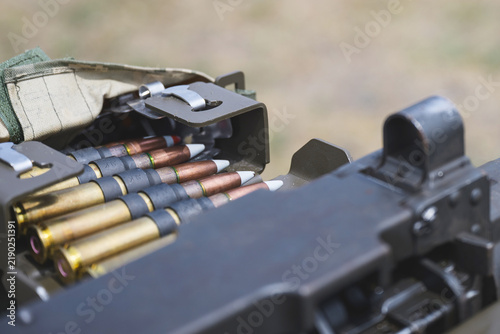 Konstfotografi Close up view of linked ammunition cartridges arranged in a metal ammunition box beside a heavy machine gun