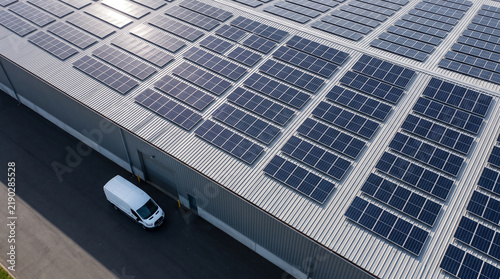 Aerial view of a white delivery van parked at a warehouse with solar panels on the roof