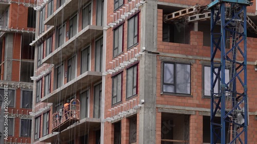 Construction workers ascending beside an unfinished multistory building, showing active high rise construction, urban development and building site operations
