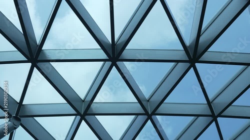 Geometric glass dome canopy featuring steel grid architecture against blue sky.