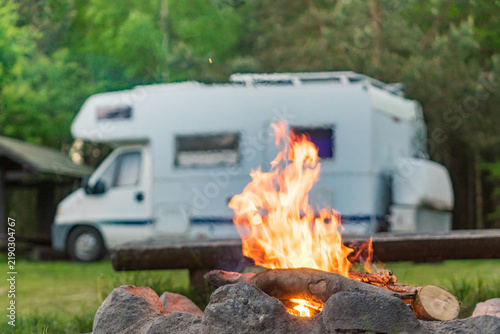 Camping on nature with cozy campfire and motorhome in serene forest setting