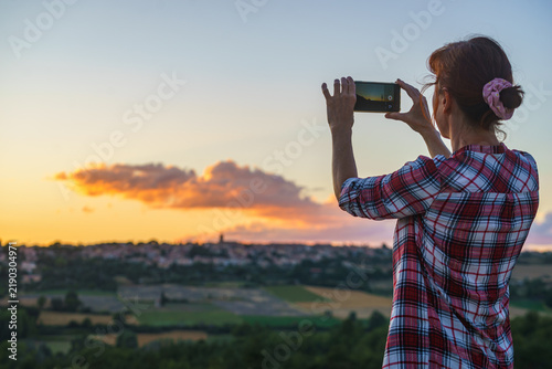Woman taking picture from sunset over hilltop Puimoisson village, Provence France