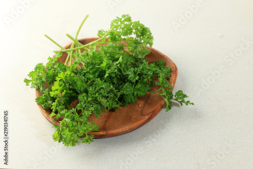 Bild auf Leinwand Fresh parsley on a rustic wooden plate.