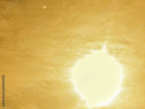 Burning sun radiates a brilliant orange glow, while soft clouds gently drift across the luminous sky. The sunlight creates a dramatic and warm atmosphere, making the scene ideal for themes of energy, 