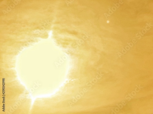 Burning sun radiates a brilliant orange glow, while soft clouds gently drift across the luminous sky. The sunlight creates a dramatic and warm atmosphere, making the scene ideal for themes of energy, 