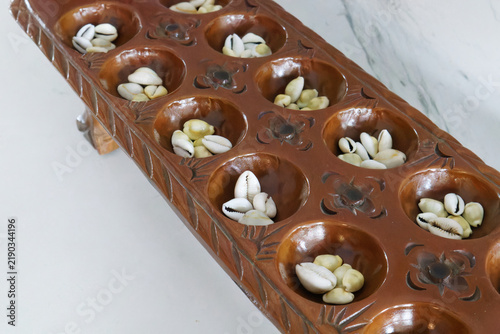 Bild auf Leinwand Mancala Carved Wooden Board Game with Cowrie Shells for Play