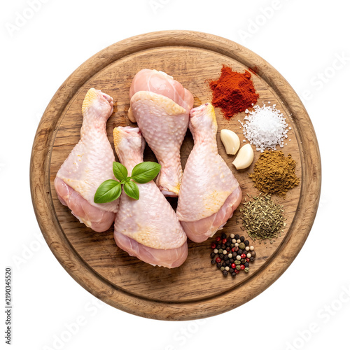 Raw chicken drumsticks with spices and herbs on wooden cutting board provide essential ingredients for fresh culinary preparation and home cooking recipes.