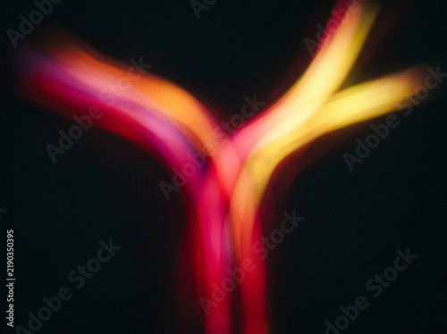 Vibrant glowing light trails creating abstract shapes against a dark black background