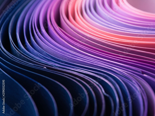 Vibrant purple and pink curved paper strips forming abstract waves and layered patterns