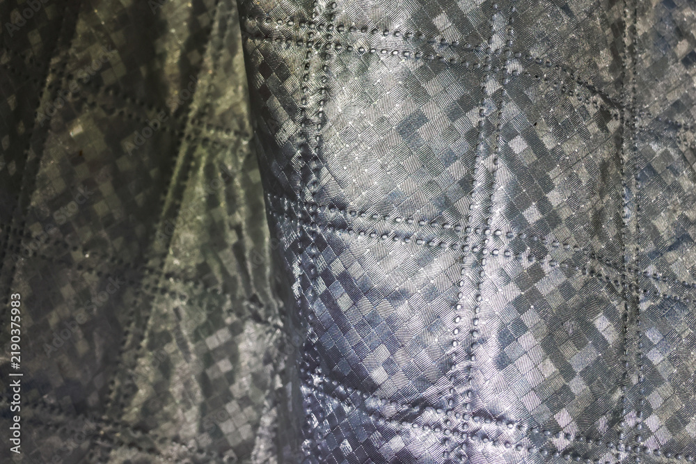 Obraz premium Gray textured fabric with stitched geometric pattern and metallic sheen creating abstract textile background