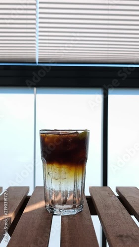 Iced espresso coffee with tonic on a wooden table in morning sun