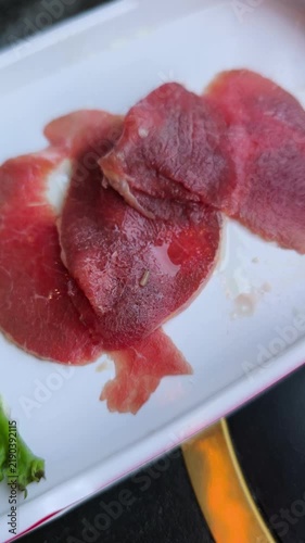 Preparing thinly sliced beef for barbecue with a visible larva, highlighting serious food safety and unhygienic conditions