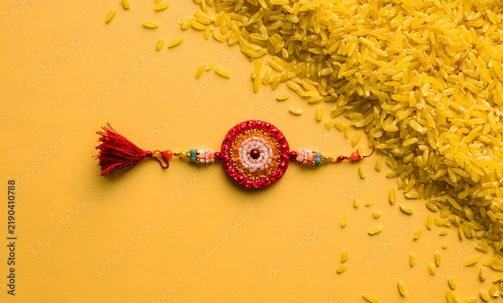 Obraz premium Raksha Bandhan, an Indian holiday adorned with intricate Rakhi patterns and yellow backgrounds featuring rice grains. It's a cherished traditional wristband representing the bond between sisters and b