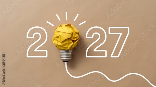 Creative 2027 concept featuring a crumpled yellow paper lightbulb on a smooth beige background, representing innovation and, future planning