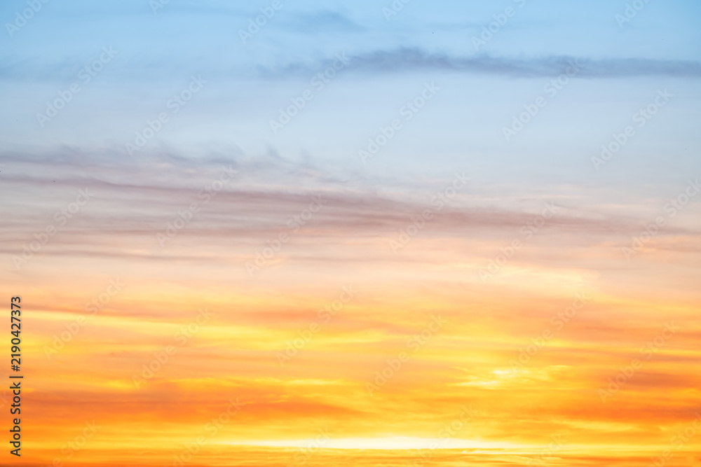 Fototapeta premium Sunset or sunrise sky with a vibrant gradient of orange, gold, and soft blue. Clear atmosphere with wispy clouds. Peaceful, natural light background. hope, freedom, new day and inspirational Concepts
