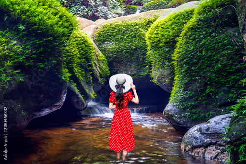 A young Asian female tourist visits a dolphin-shaped rock at Kinnari Waterfall in Bueng Kan Province, Thailand.