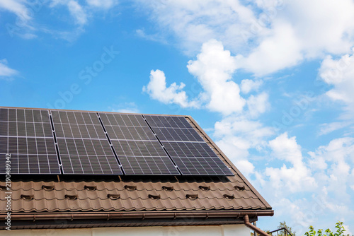 Solar panels installed on private house roof under bright blue sky