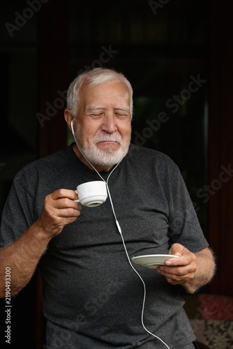 Elderly man enjoys coffee while listening to music at home on a quiet afternoon