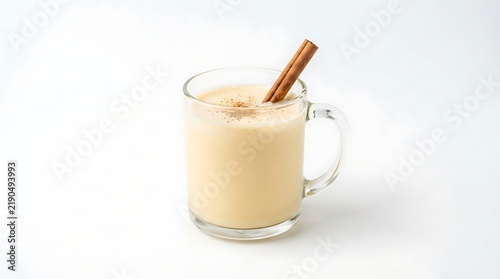 A warm glass of eggnog with a cinnamon stick garnish on a white background