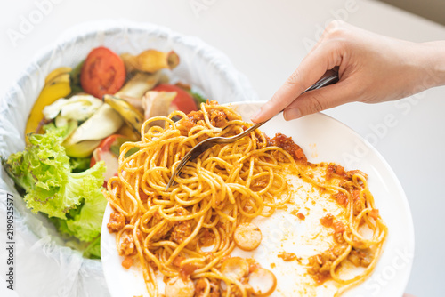 Foto Compost from leftover food asian young housekeeper woman, female hand holding spaghetti plate use fork scraping waste, food throwing away into garbage, trash or bin