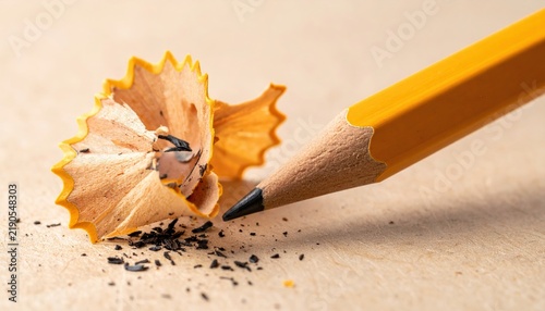 Sharpened wooden pencil with graphite tip and curled wood shavings, creative stationery concept