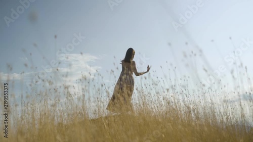 Graceful woman in silk skirt dancing over blue sky background