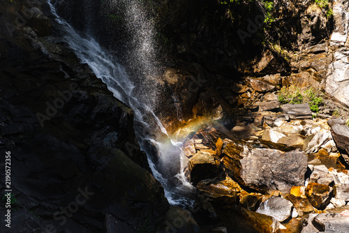 Картината върху платно Mountain waterfall cascading over rocky cliff with rainbow mist for ecotourism c