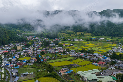 Small farming village with rice fields by mountain fog - Aerial view