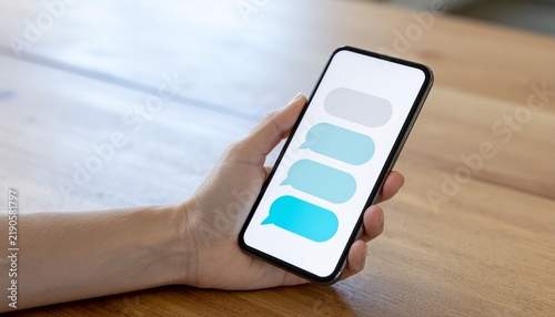 Obraz na płótnie 木製テーブルでスマートフォンを持つ手を写したデジタルイメージ