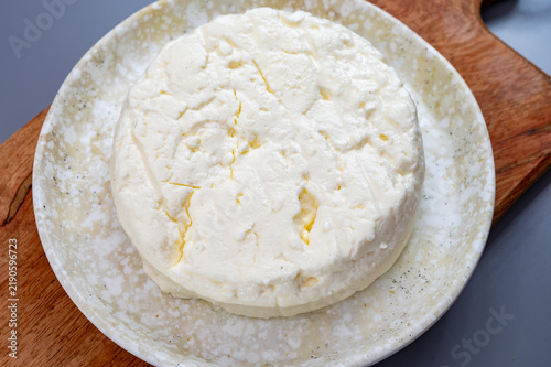 Fresh young chèvre goat cheese from France on ceramic plate. Creamy artisanal soft cheese with hite color and delicate fresh texture.