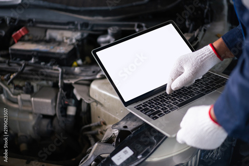 Male mechanic connecting laptop to car engine system for diagnostic test