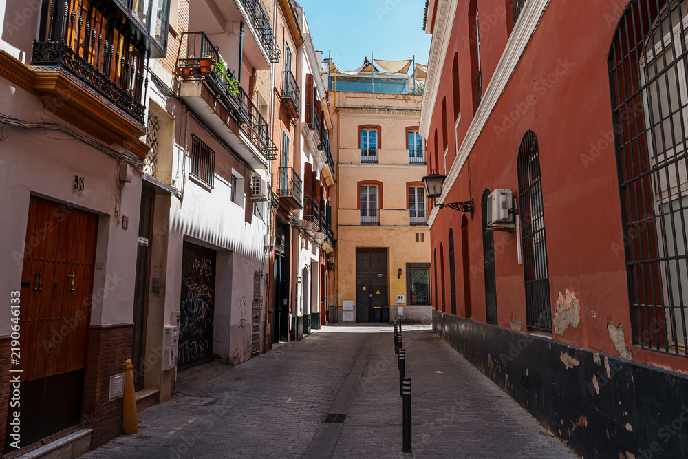 Fototapeta premium Narrow historic street lined with balconied buildings in Seville old town