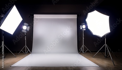 a professional photography studio with a white backdrop and two large studio lights pointing towards the center