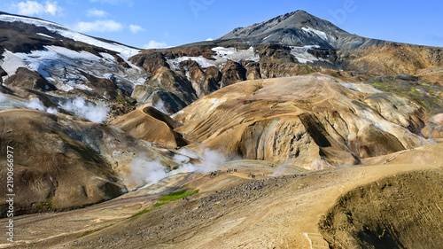Quadro su tela Hikers explore steaming geothermal hot springs among colorful snow-streaked mountains near Kerlingarfjoll, Icelandic highlands