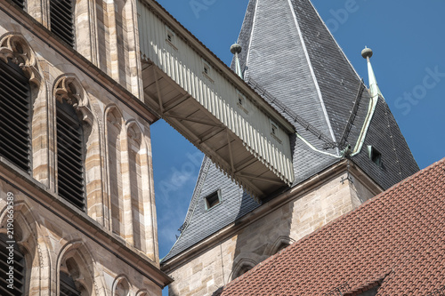 Detail Untersicht Türme der gotischen Stadtkirche St Dionys in Esslingen am Neckar mit Verbindungsbrücke zur Stabilisierung vor blauem Himmel im steilen Oberlicht.