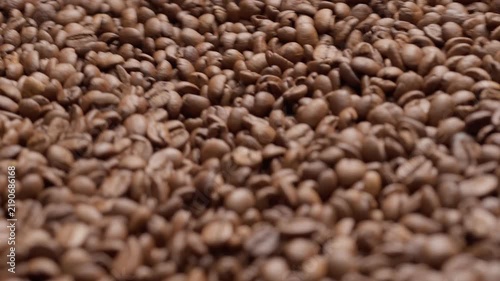 Freshly roasted coffee beans cooling in roaster tray, closeup
