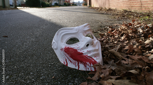 Discarded halloween mask bloodstain suburban alleyway autumn pavement white plastic