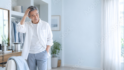 明るい自宅のドレッシング空間で髪を整える男性 健康的な美肌と穏やかな表情を生かした美容広告向けコピースペース