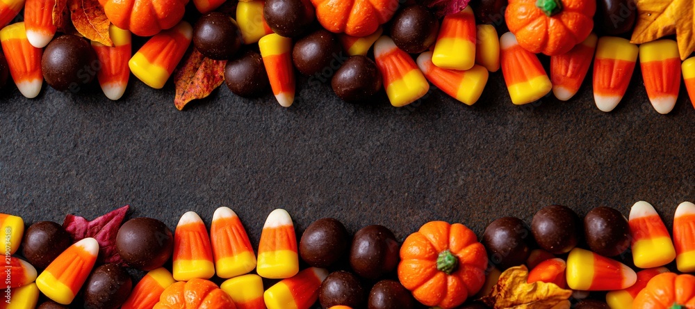 Obraz premium Halloween candy corn and chocolate with pumpkins and autumn leaves framing empty center