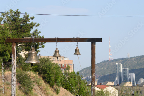 Fotografie Commercial stock photo of church bells hanging against a city skyline