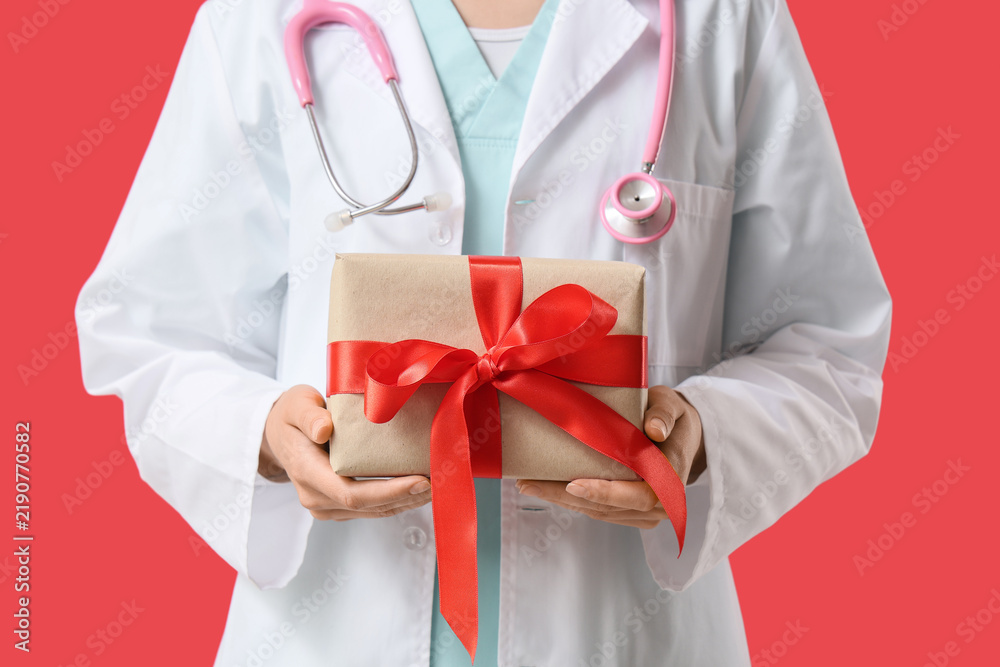 Obraz premium Healthcare appreciation and medical gift, doctor holding a present with red ribbon for patient care gratitude and hospital staff recognition