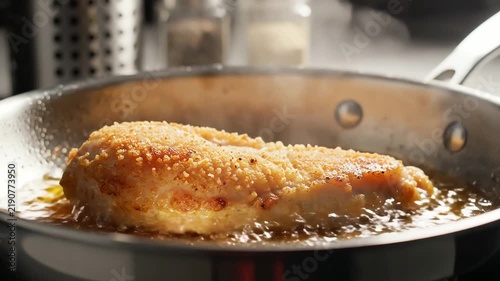 Breaded chicken breast frying in a pan