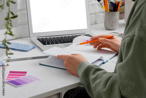 Female interior designer with notebook working at table in studio